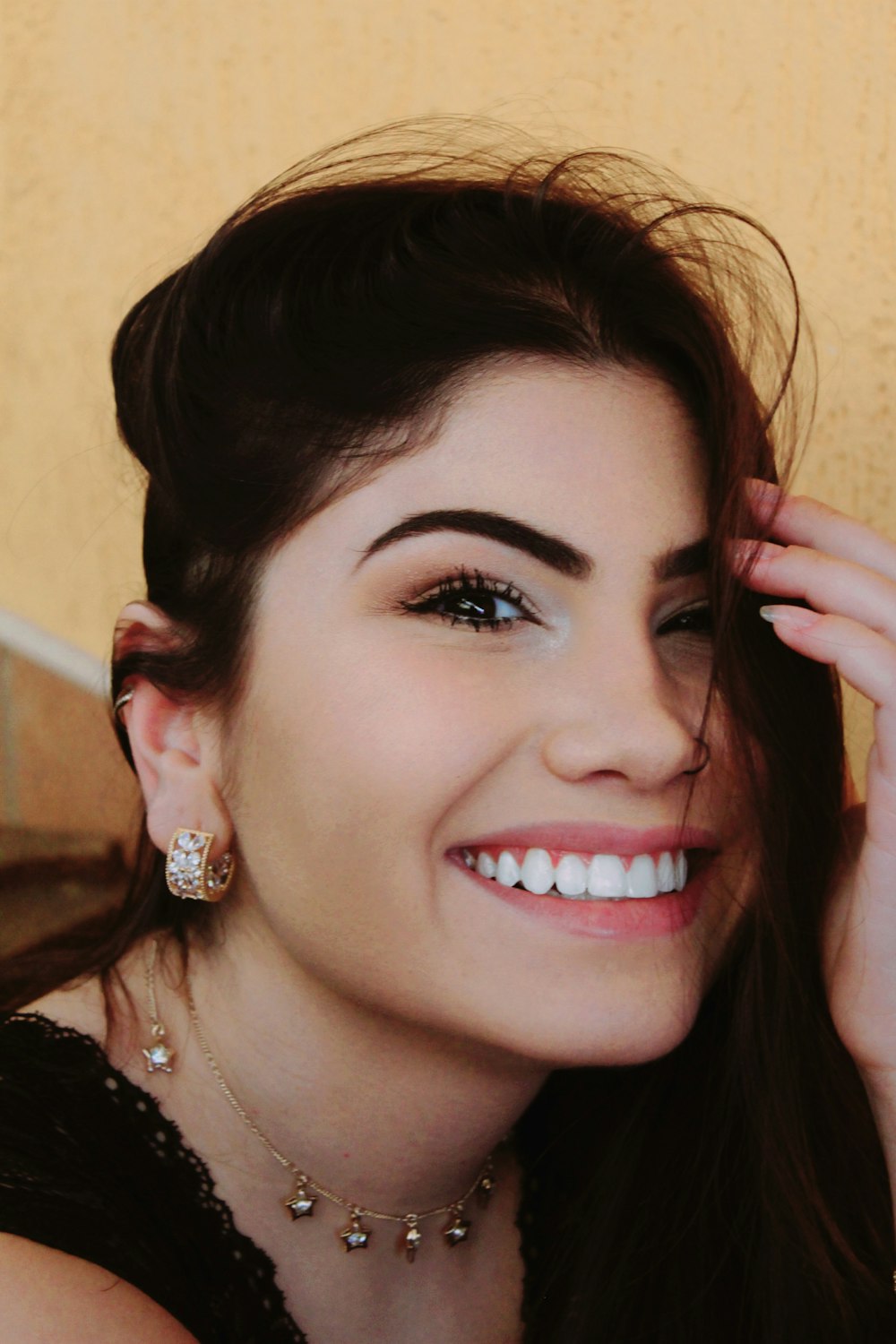 a woman wearing a necklace and earrings smiling