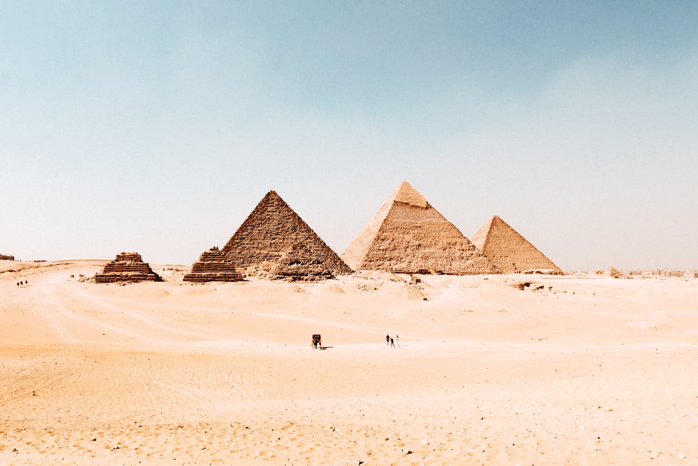 um grupo de pirâmides no deserto com um fundo do céu