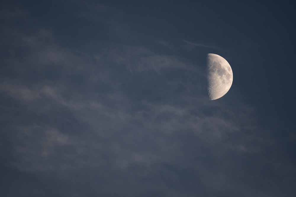 a half moon is seen in a cloudy sky
