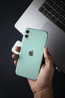 a person holding an iphone in front of a laptop