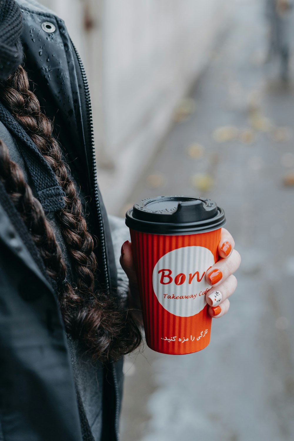 a woman holding a red coffee cup in her hand