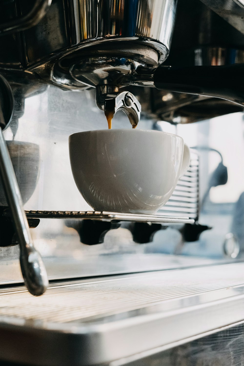 a cup of coffee being poured into a coffee machine