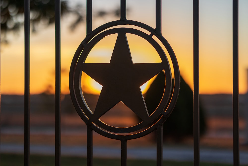 a star on a fence with the sun setting in the background