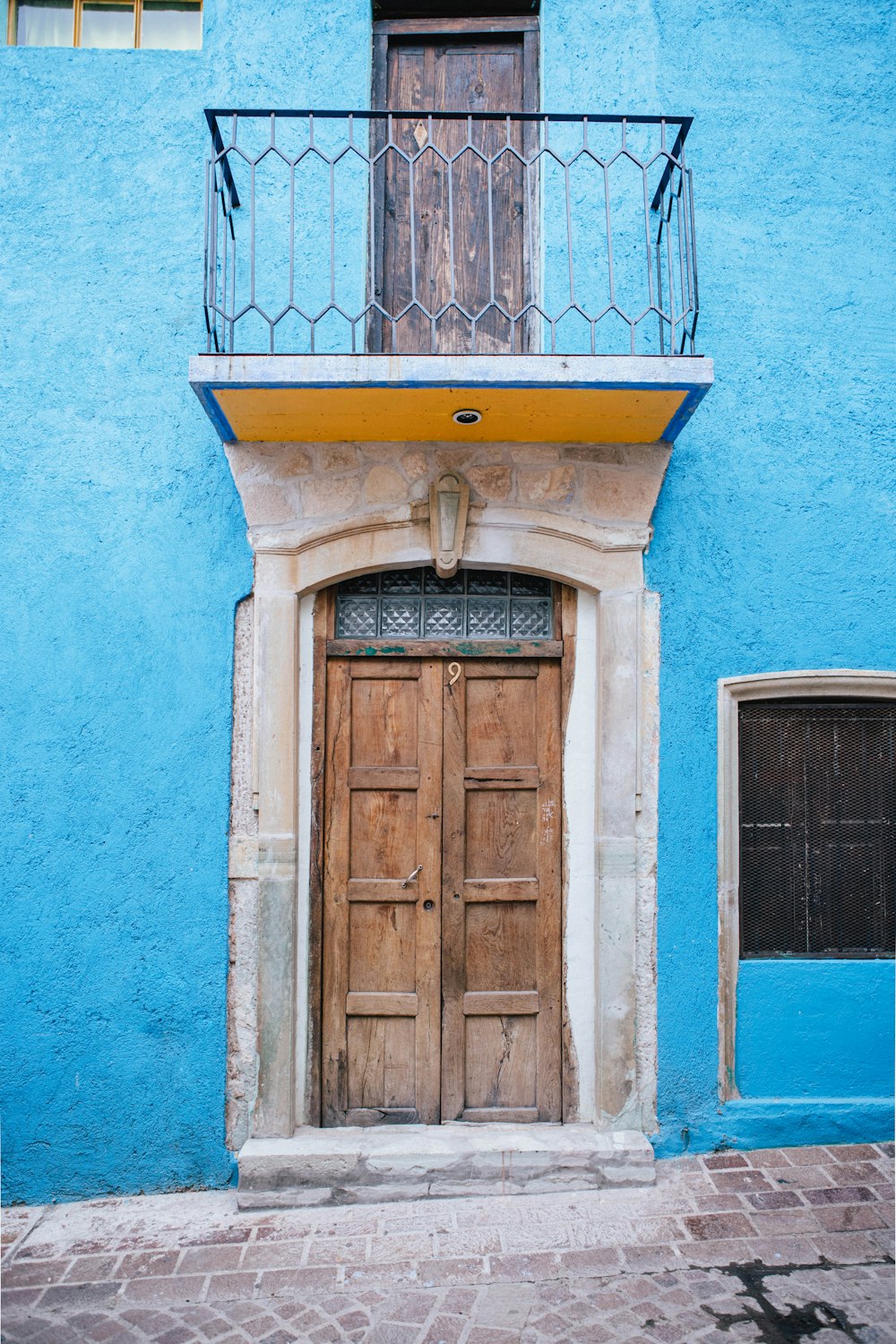 a blue building with a wooden door and balcony