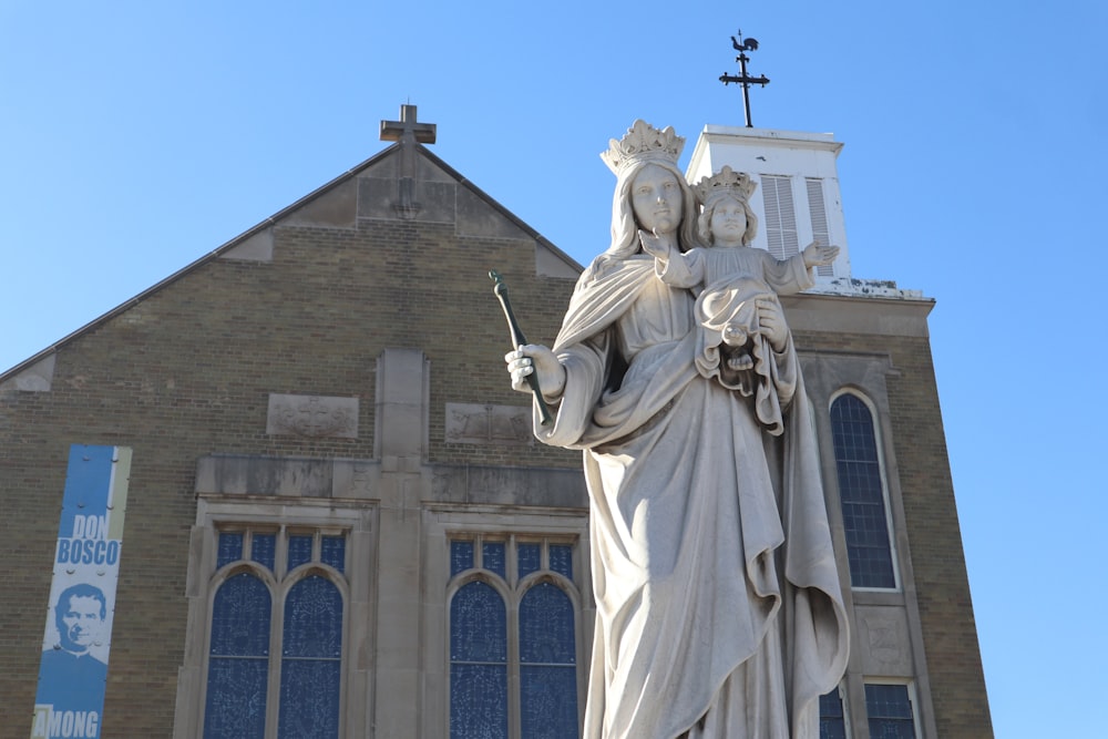 a statue of a woman holding a cross in front of a church