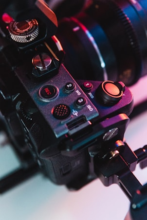 Close-up view of a professional camera with a focus on its mechanical controls and dials. The image highlights the details of buttons marked with functions like REC, WB, and IRIS. The camera setup appears to be on a stabilizer or tripod.