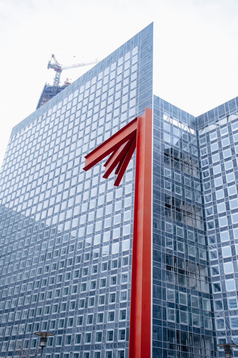 Un edificio alto con una escultura roja frente a él
