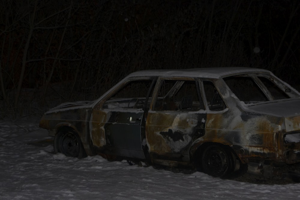 a burnt out car in the snow at night