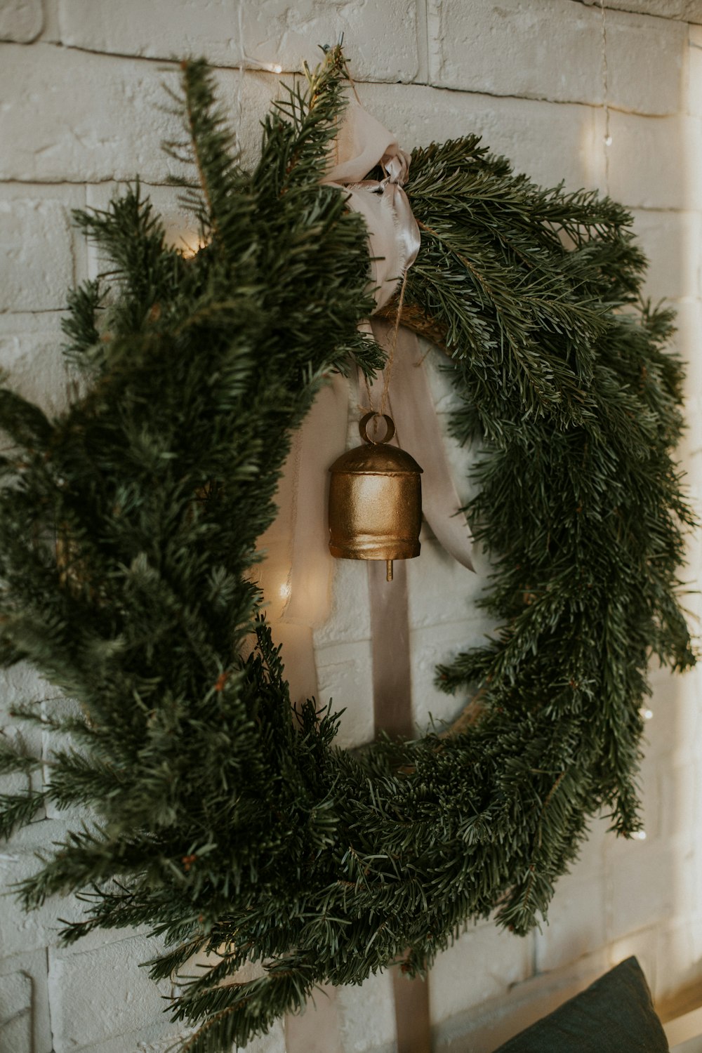 a wreath with a bell hanging on a brick wall