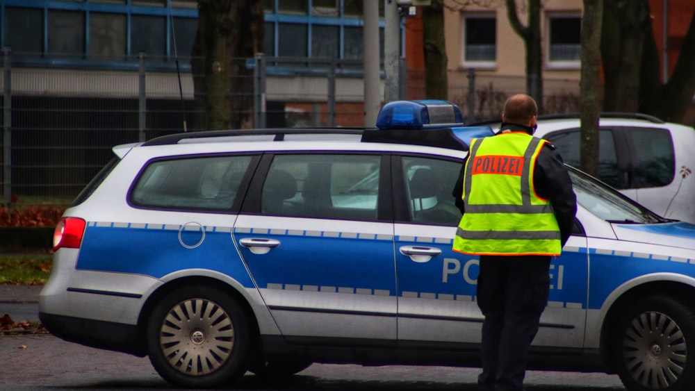 Un agente di polizia in piedi davanti a una macchina della polizia