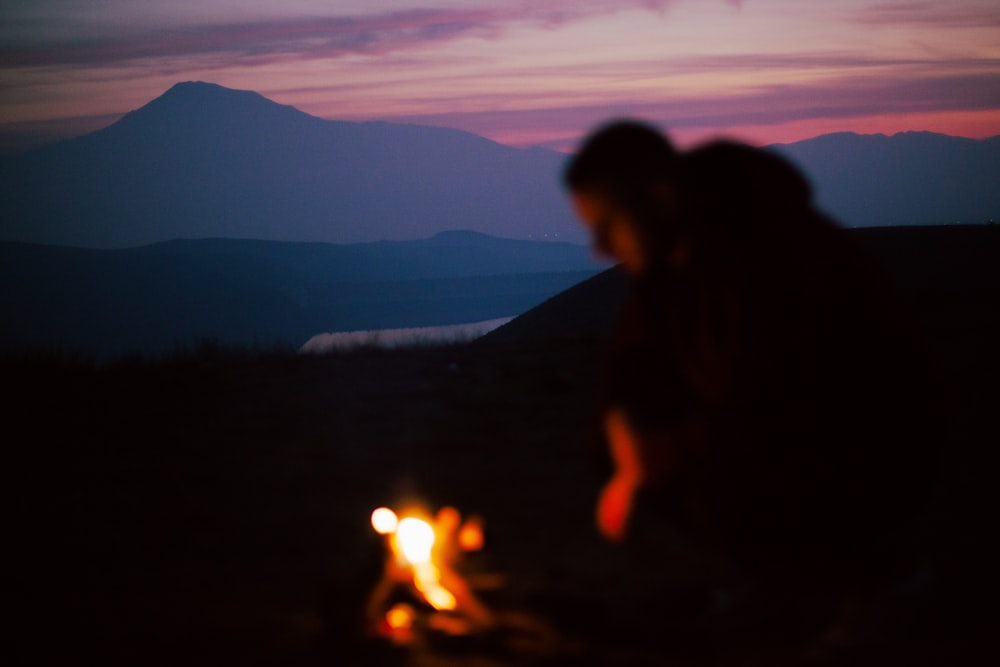 a couple of people sitting next to a fire