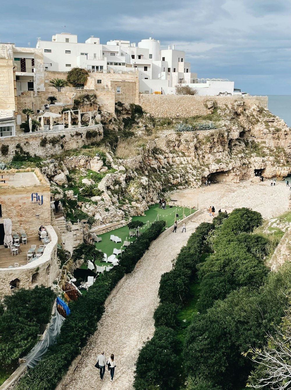 people walking on a path next to a beach