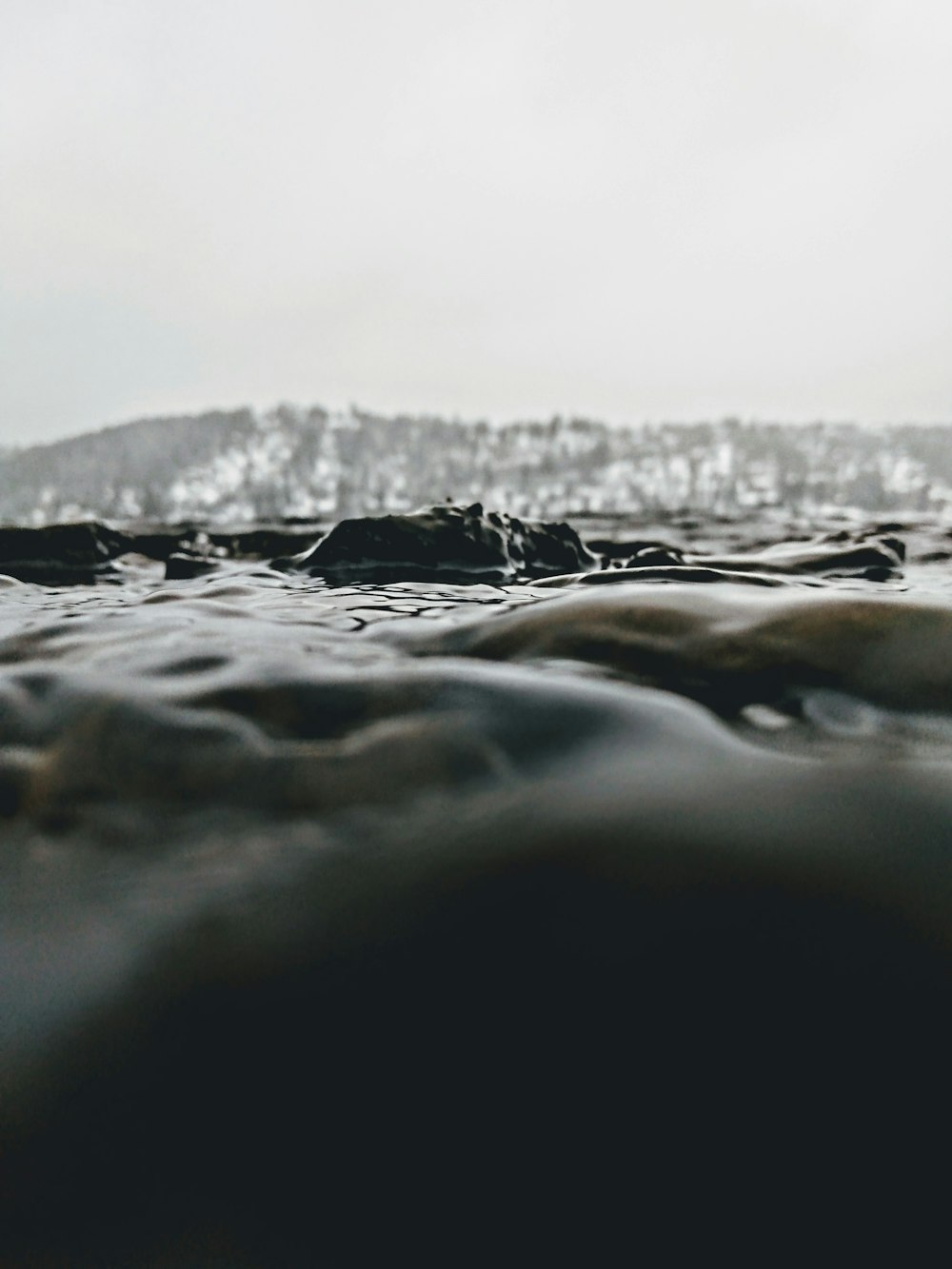 a black and white photo of water with a mountain in the background