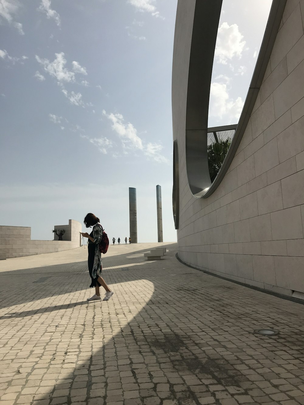 a woman walking down a brick walkway next to a building