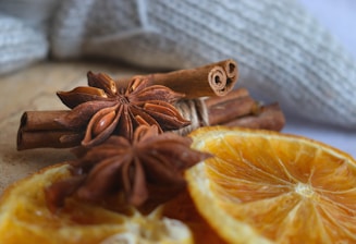 A warm, inviting scene of spices and citrus fruits arranged around amber and oud wood pieces.