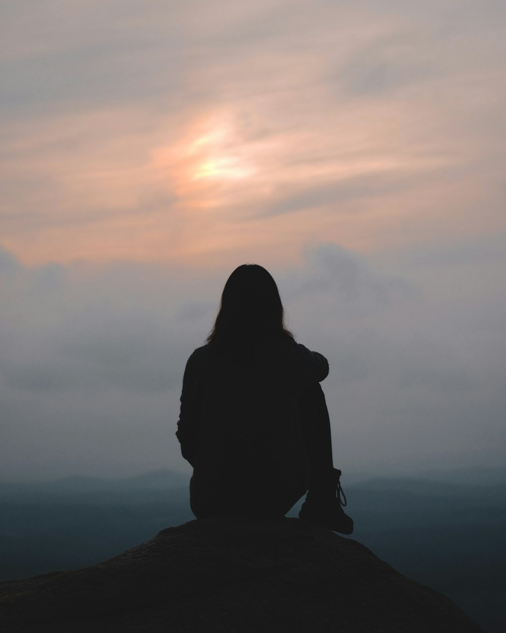 uma pessoa sentada no topo de uma colina olhando para o céu