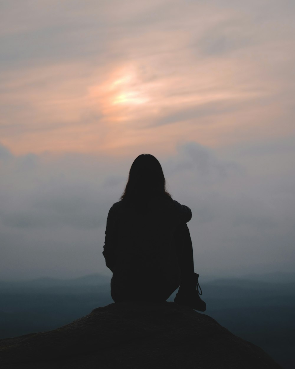 a person sitting on top of a hill looking at the sky