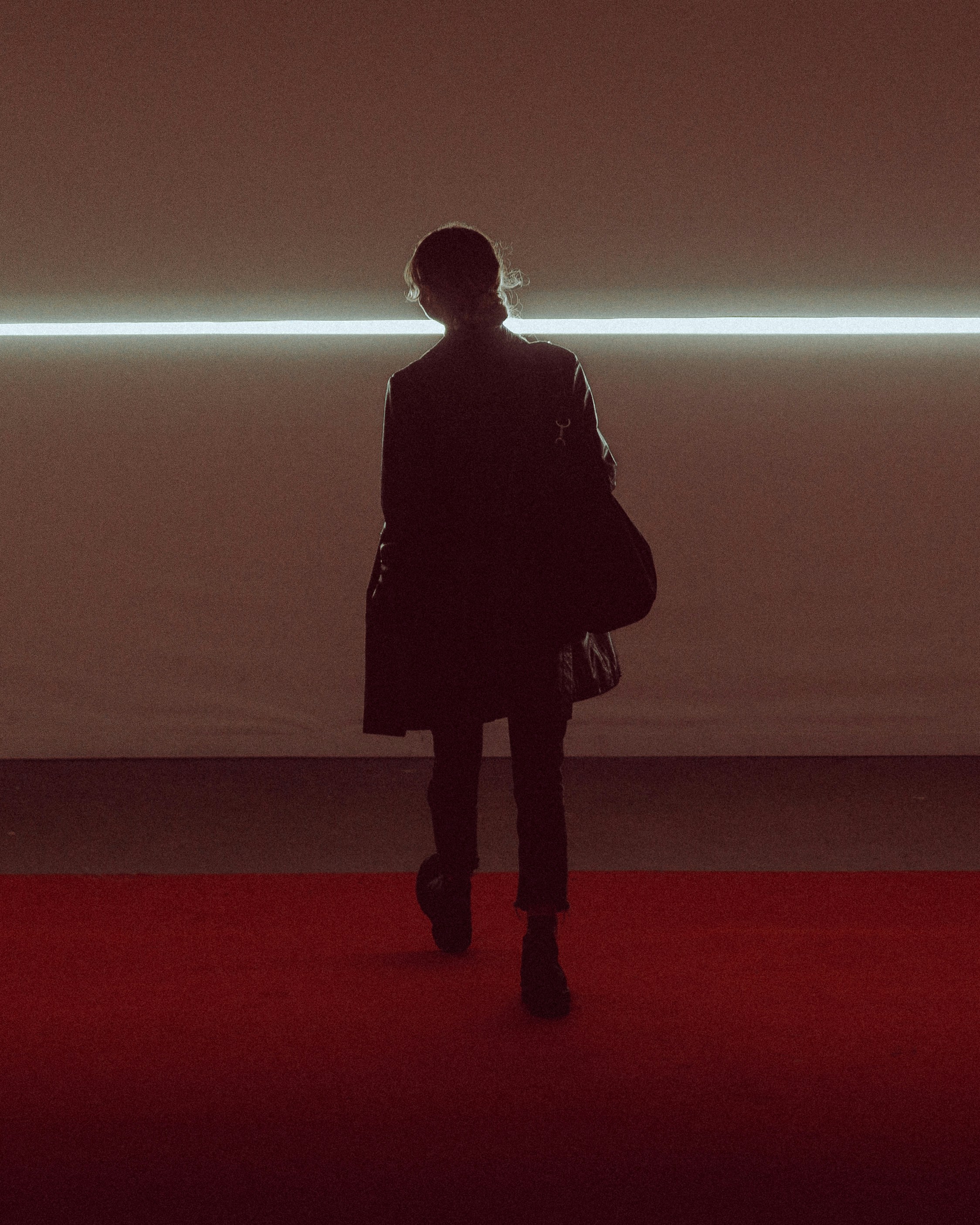 A person standing on a red carpet in front of a white wall photo – Free ...