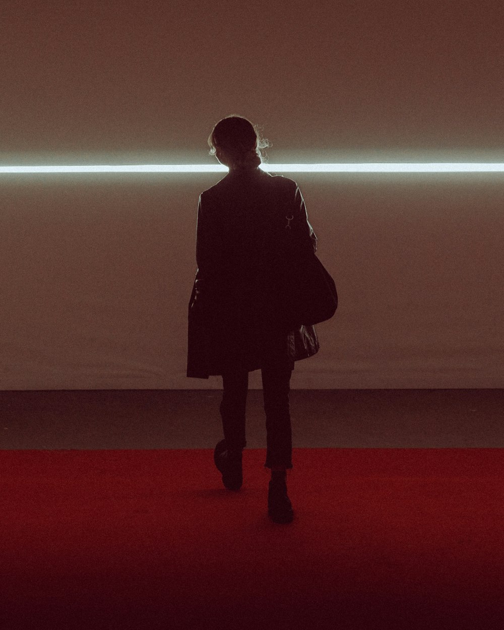 a person standing on a red carpet in front of a white wall