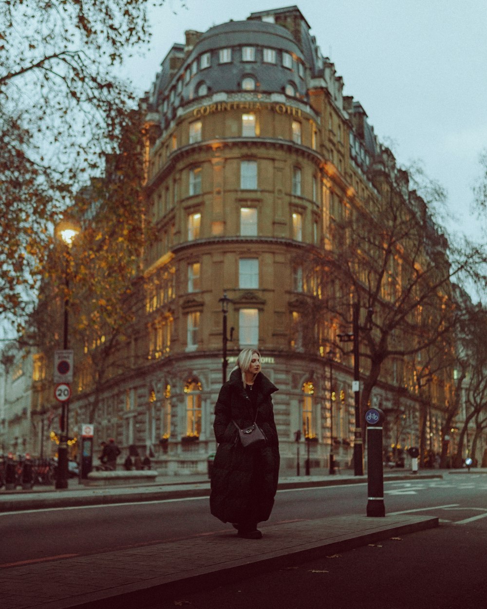 a woman walking down a street in front of a tall building