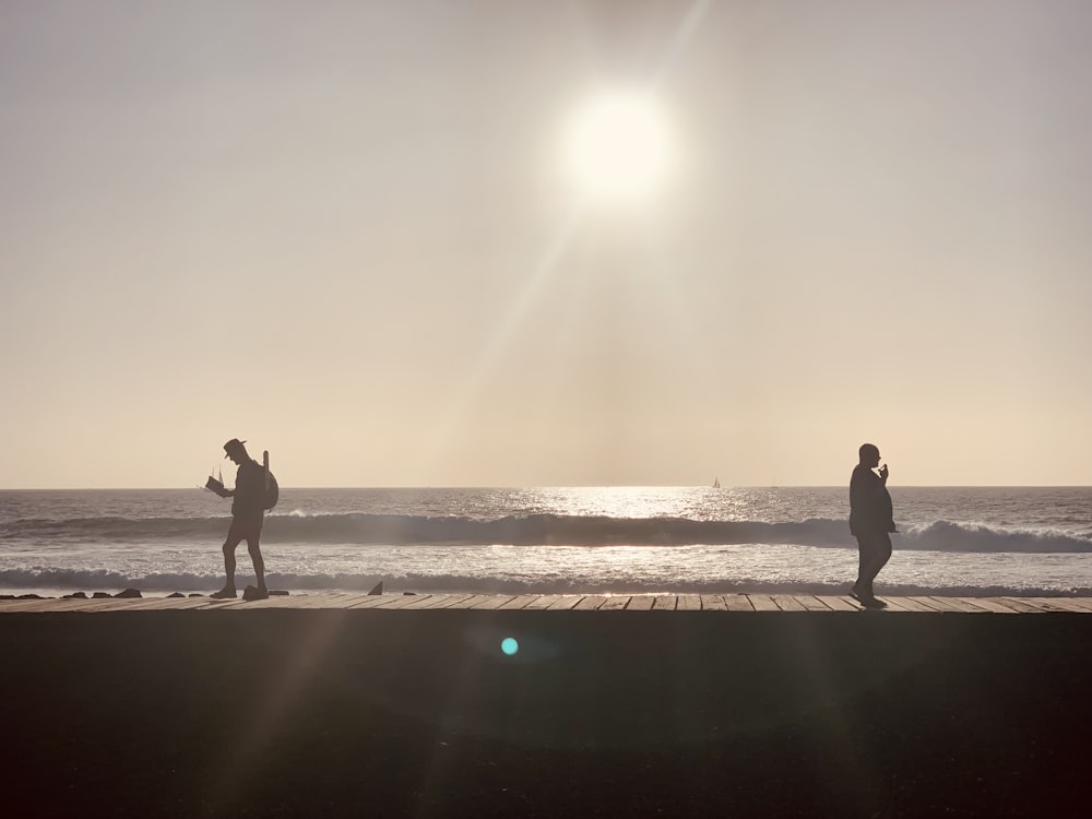 a couple of people standing on top of a pier near the ocean