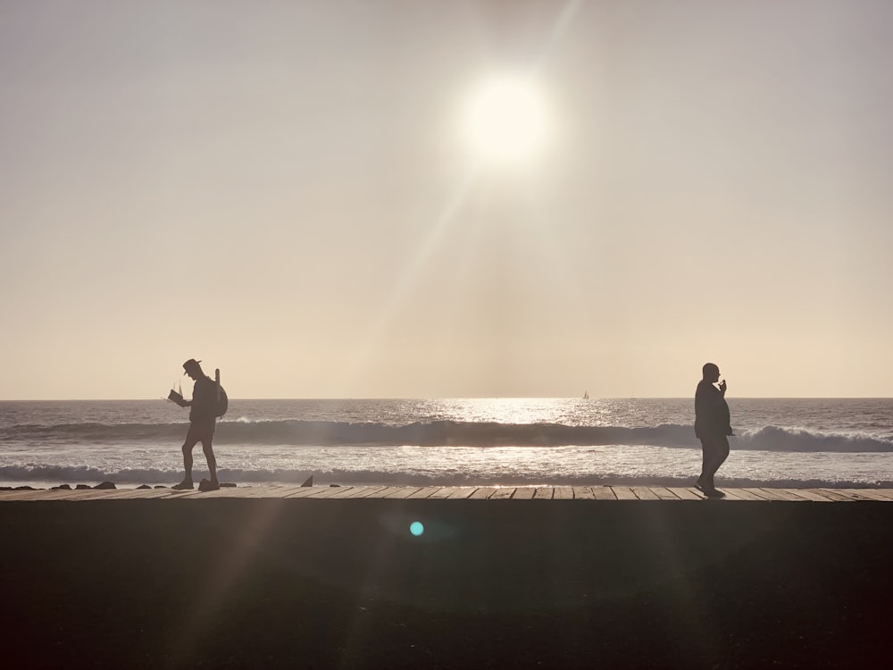 Un paio di persone in piedi sulla cima di un molo vicino all'oceano