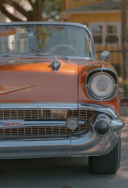 the front end of a classic car parked on the street