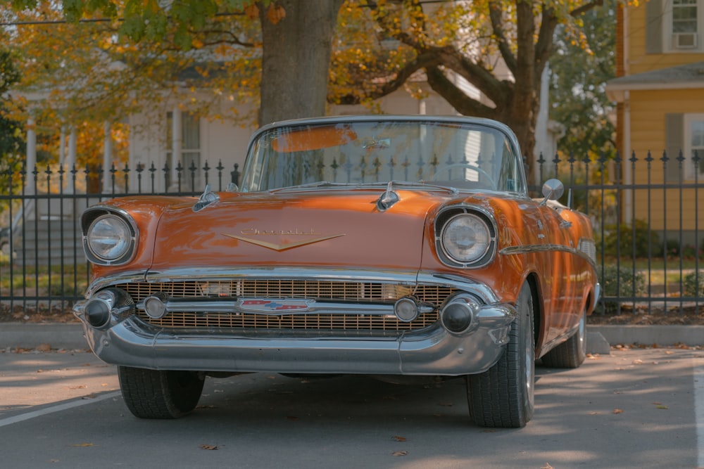 an orange classic car parked on the side of the road