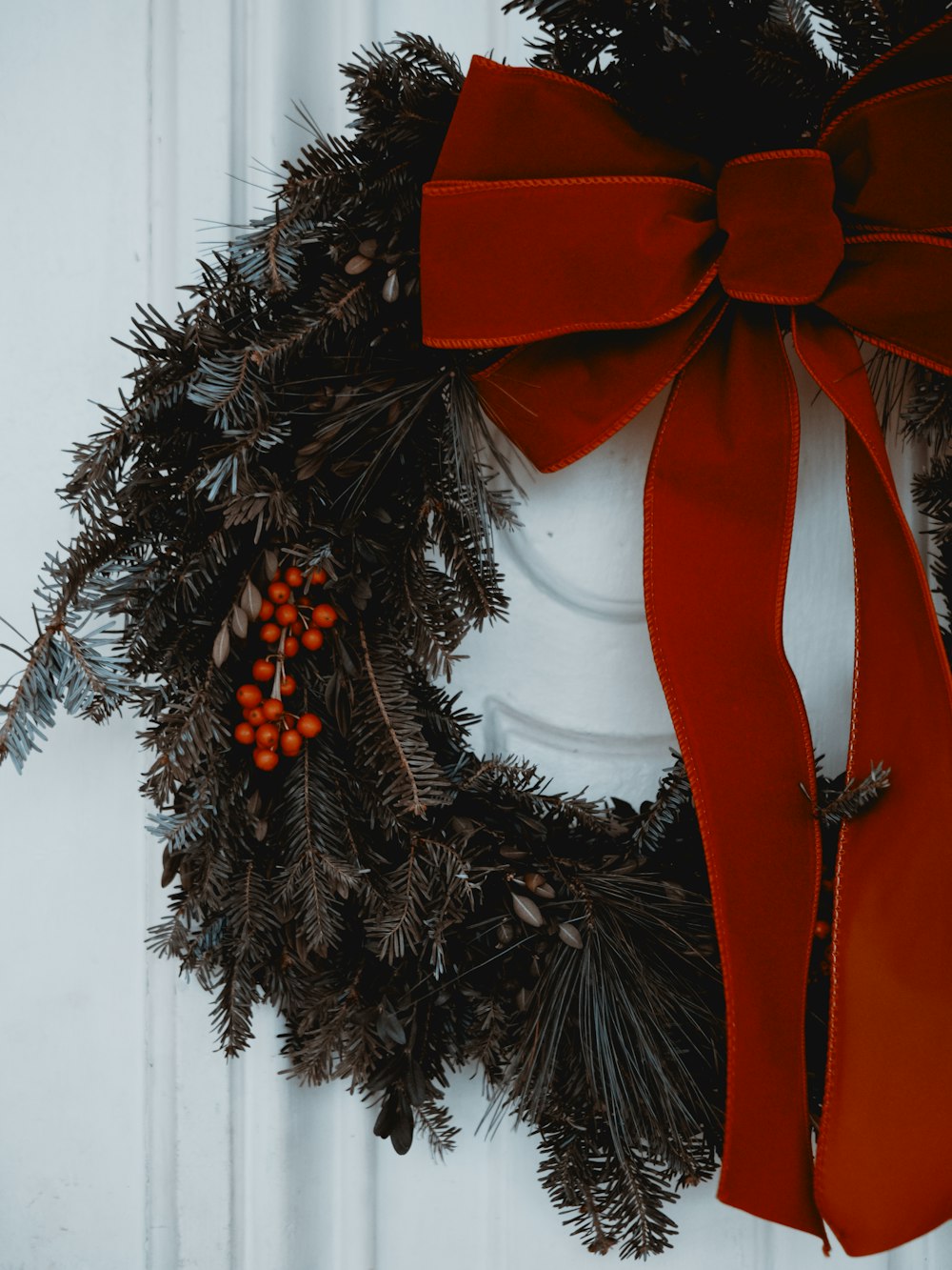 a wreath with a red bow hanging on a door