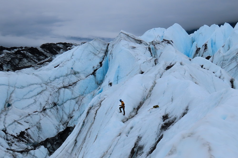 a man climbing up the side of a snow covered mountain