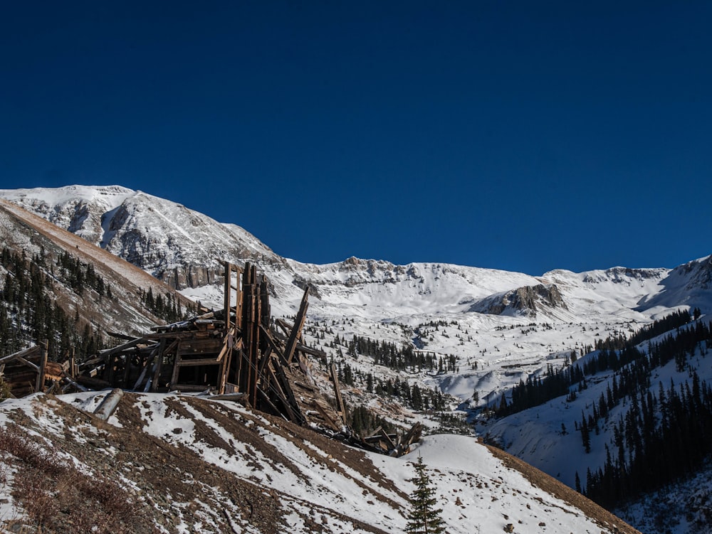 a pile of wood sitting on the side of a snow covered mountain