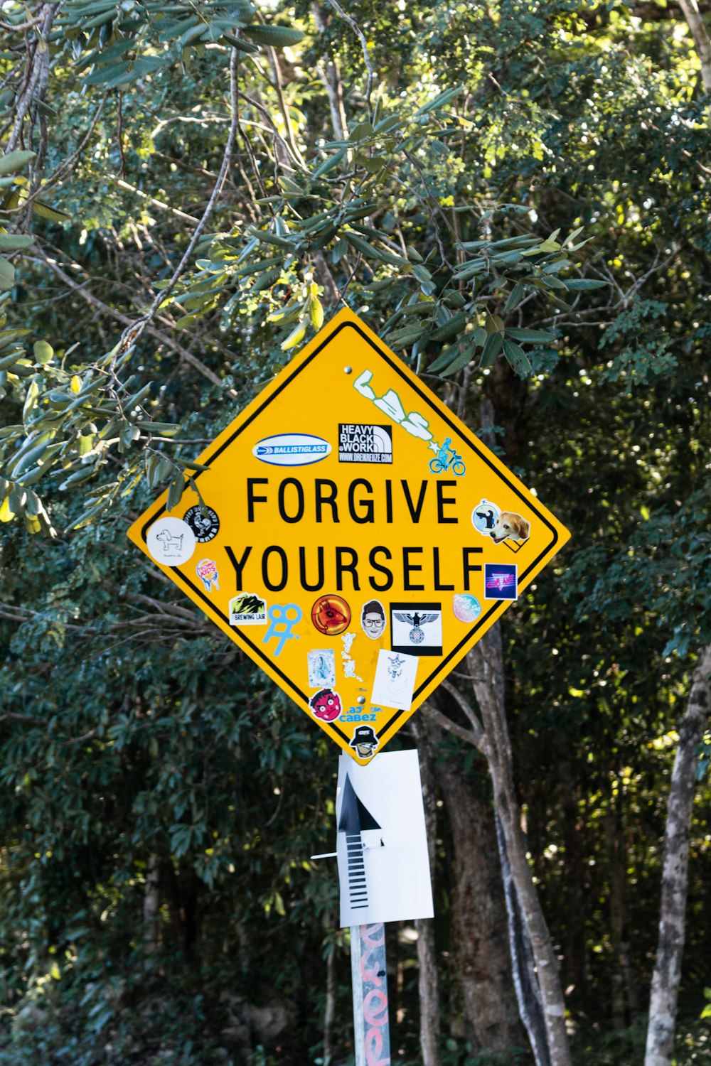 a yellow street sign with stickers on it