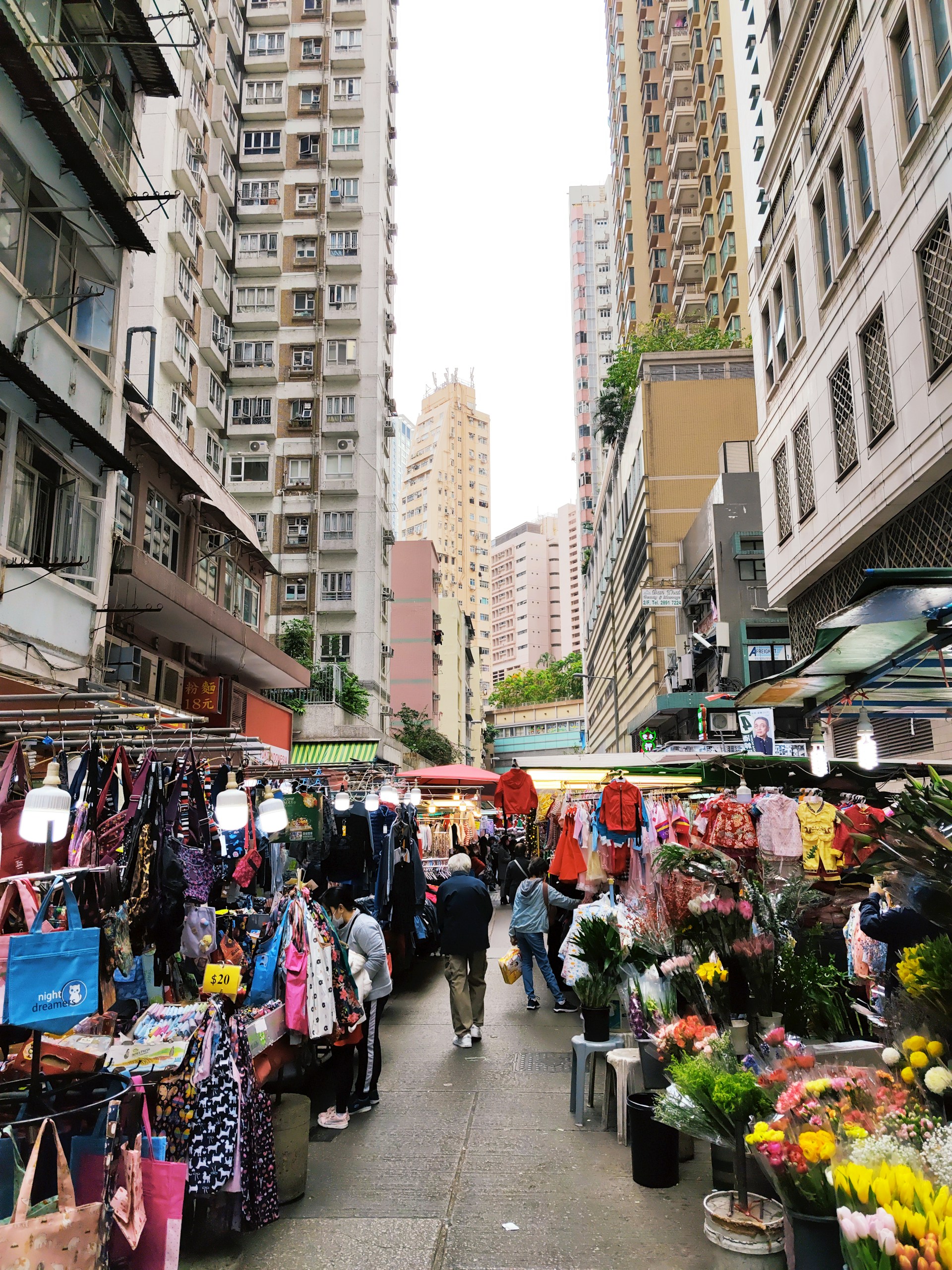 A bustling market street filled with colorful stalls and smiling vendors under vibrant awnings.