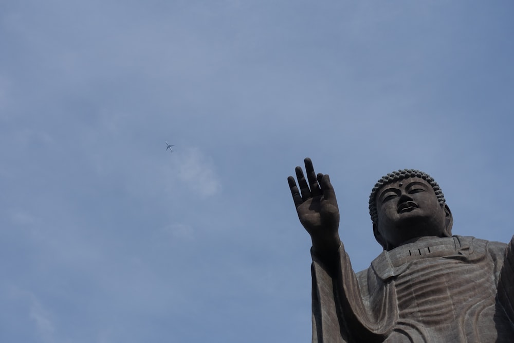 a statue of a person reaching up to the sky