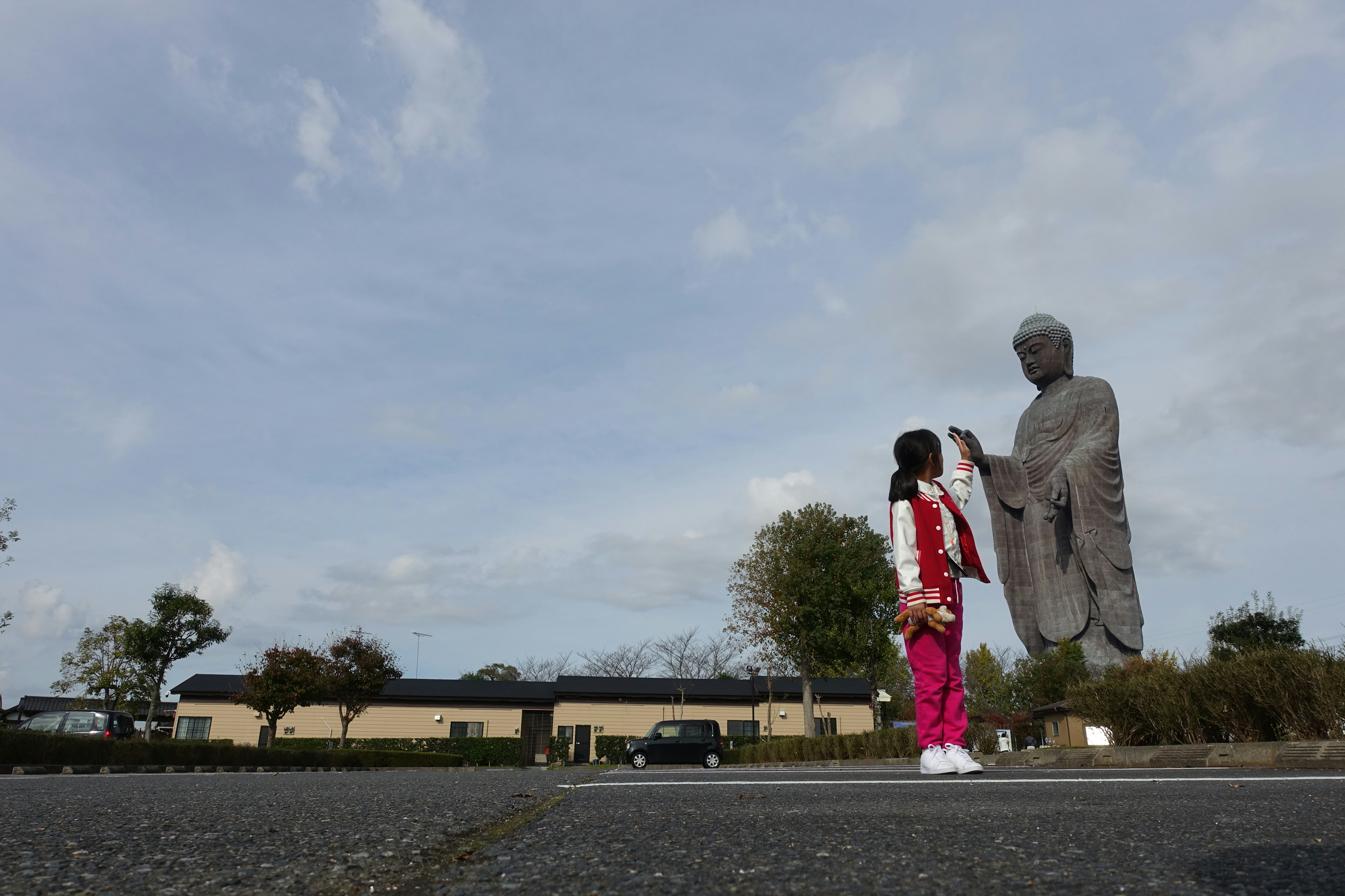 a little girl standing next to a statue