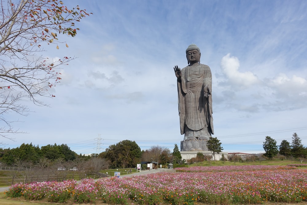 a large statue of a person in a field of flowers