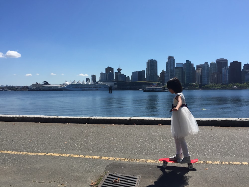 a little girl riding a skateboard down a street