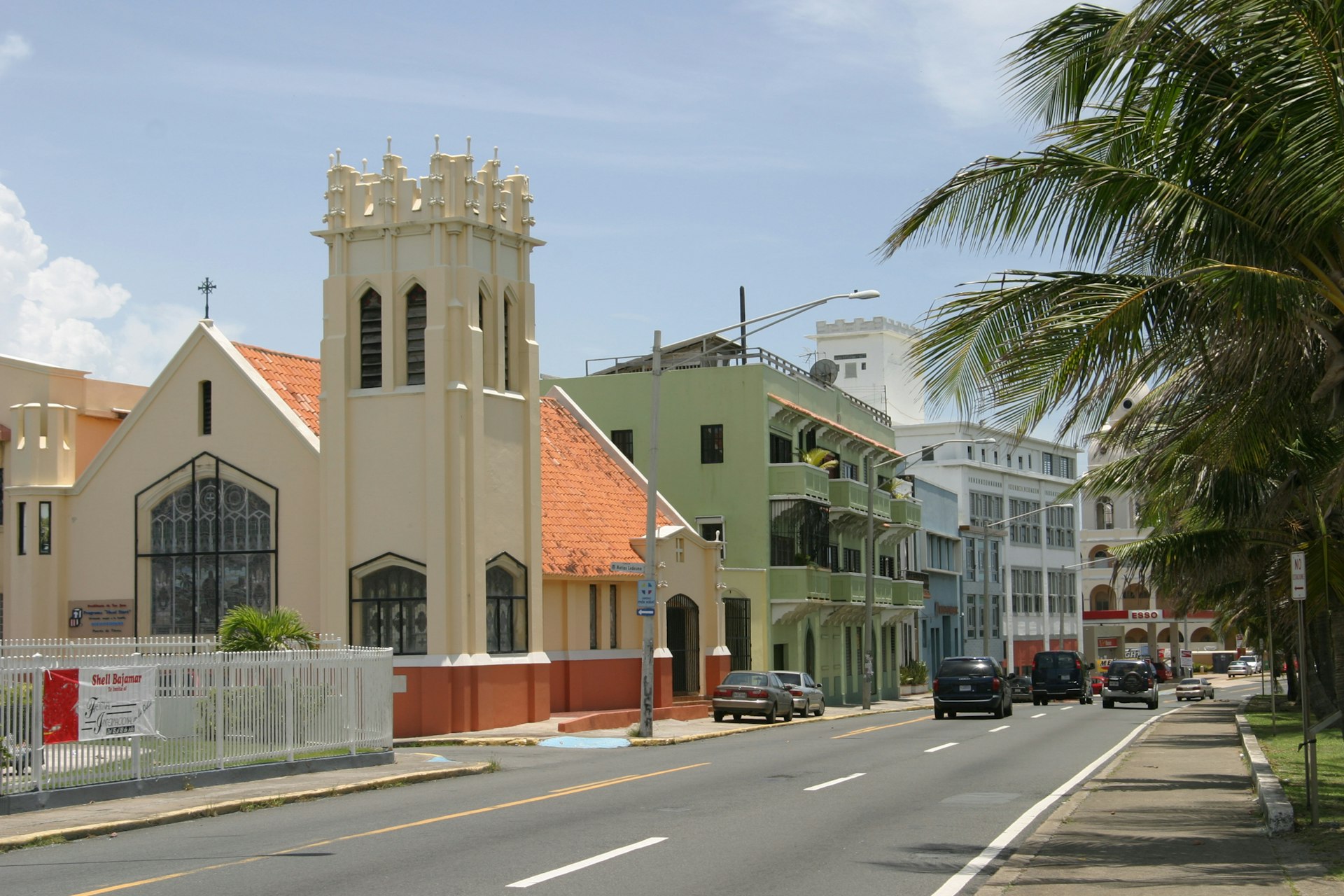 A street lined with buildings and palm trees under a clear blue sky