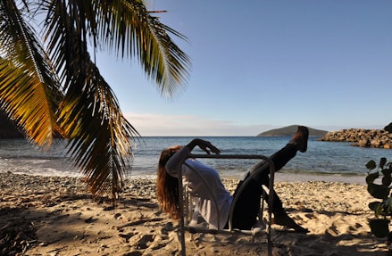a woman sitting in a chair on the beach