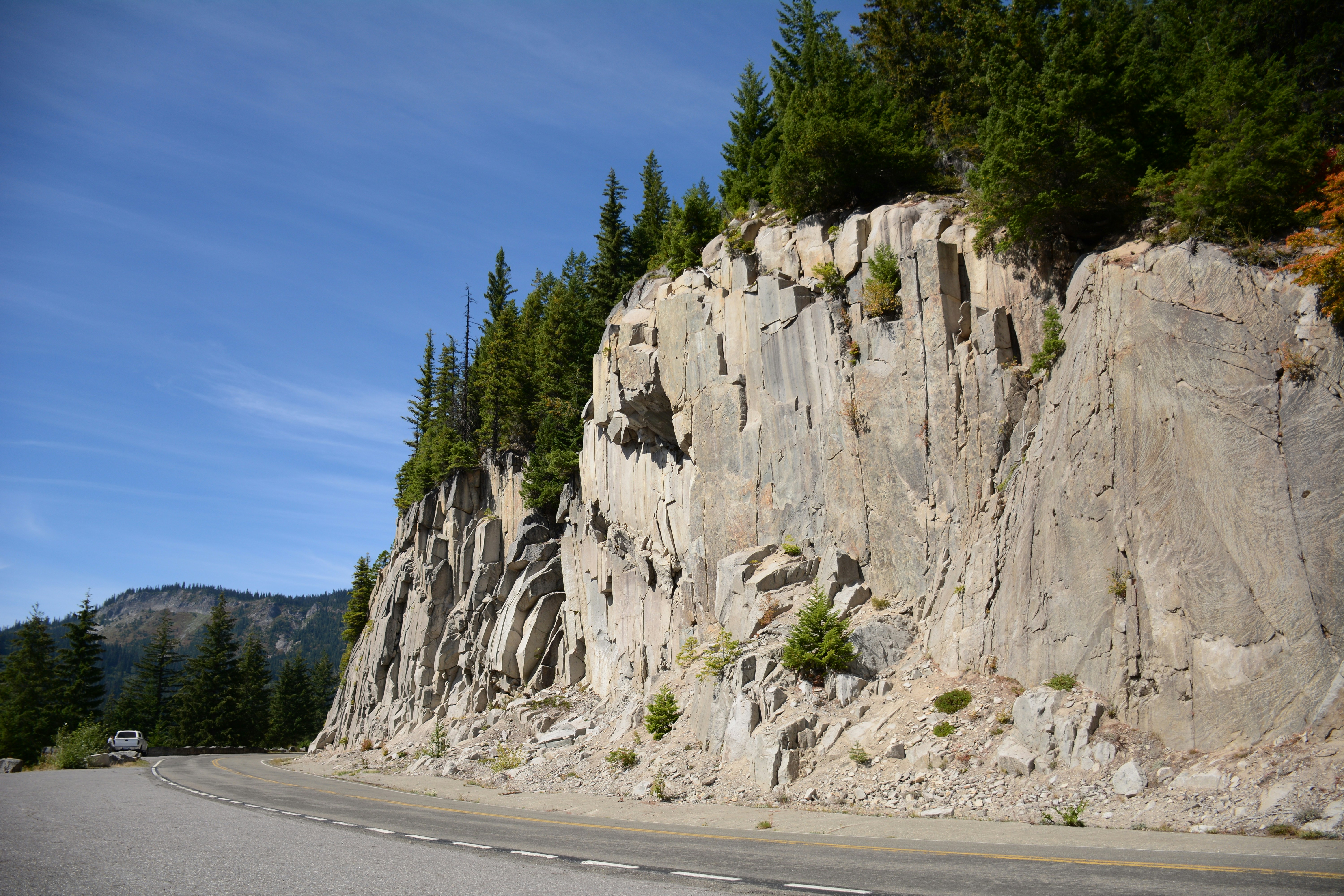 a car driving down a road next to a mountain