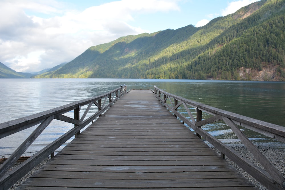 a wooden dock on a lake with mountains in the background