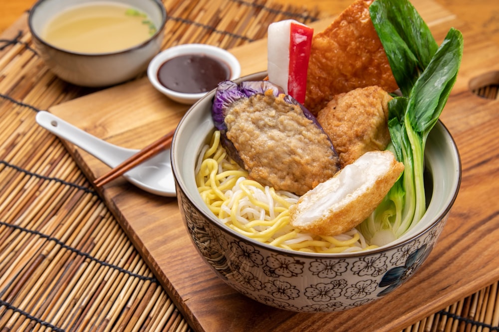 a bowl filled with noodles and meat on top of a wooden table