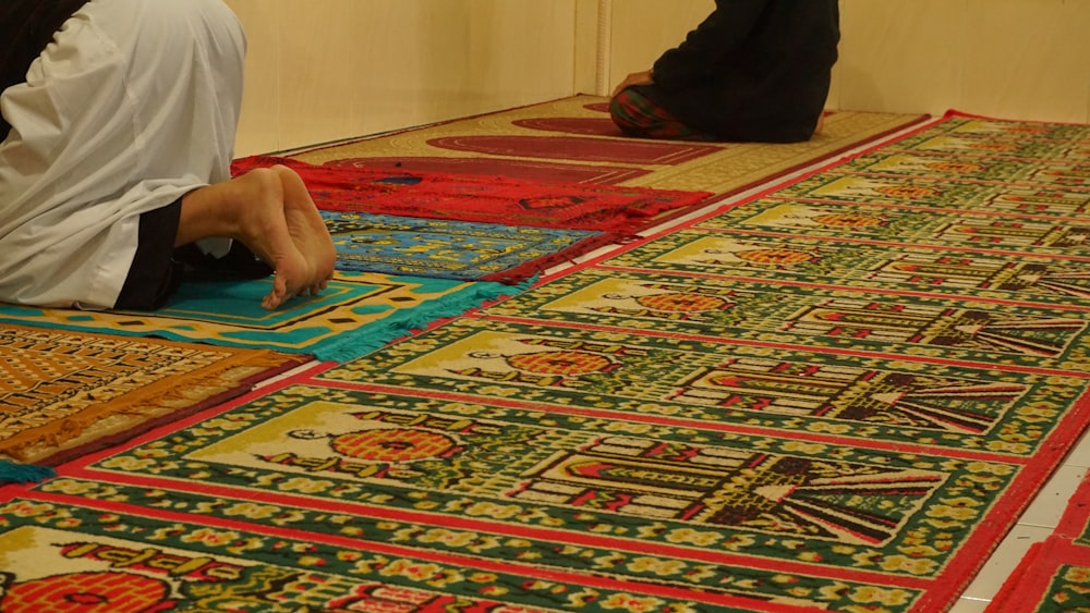 a group of men sitting on the ground working on rugs