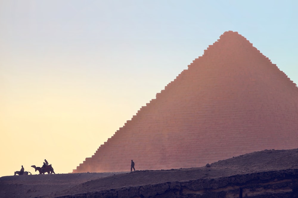 a man riding a horse next to a large pyramid