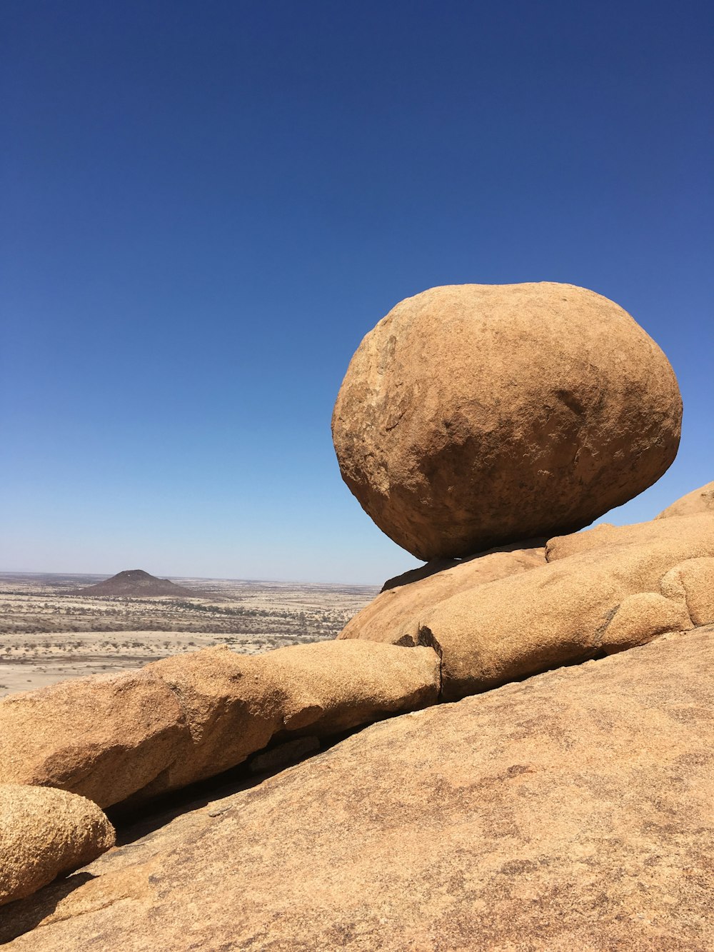 a large rock sitting on top of a dry grass field