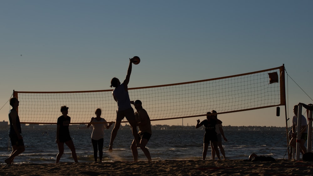 a group of people playing volleyball on the beach