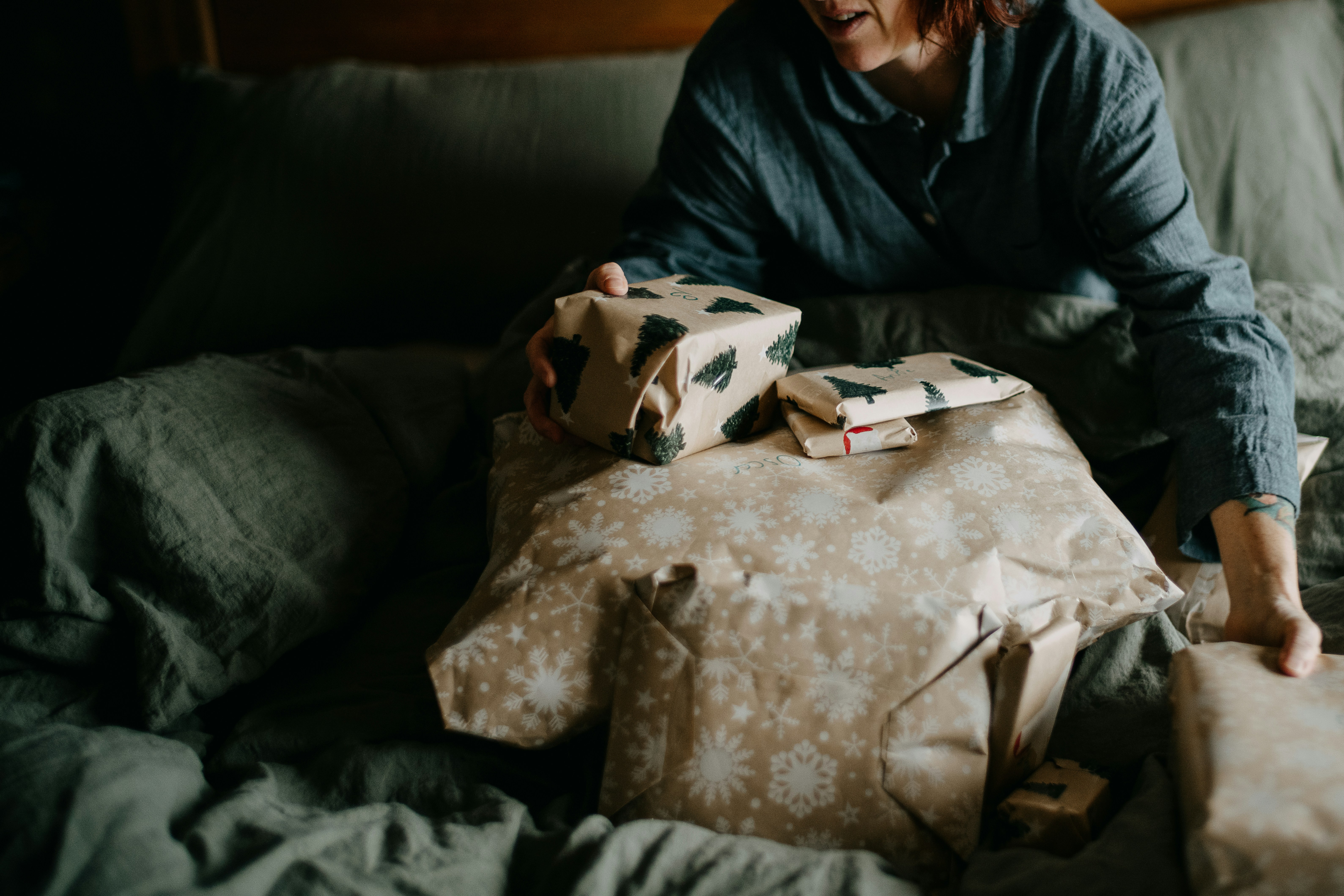 a woman sitting on top of a bed holding a wrapped present