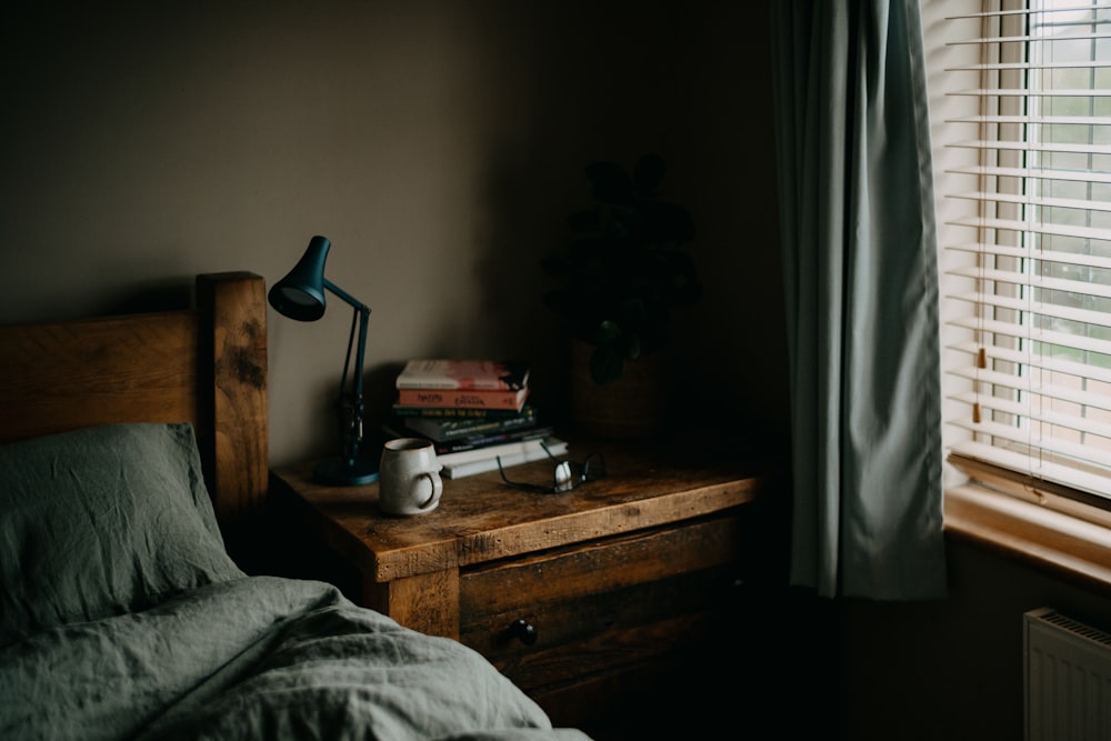 a bed sitting next to a window with a lamp on top of it