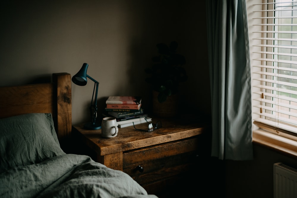 uma cama sentada ao lado de uma janela com uma lâmpada em cima dela