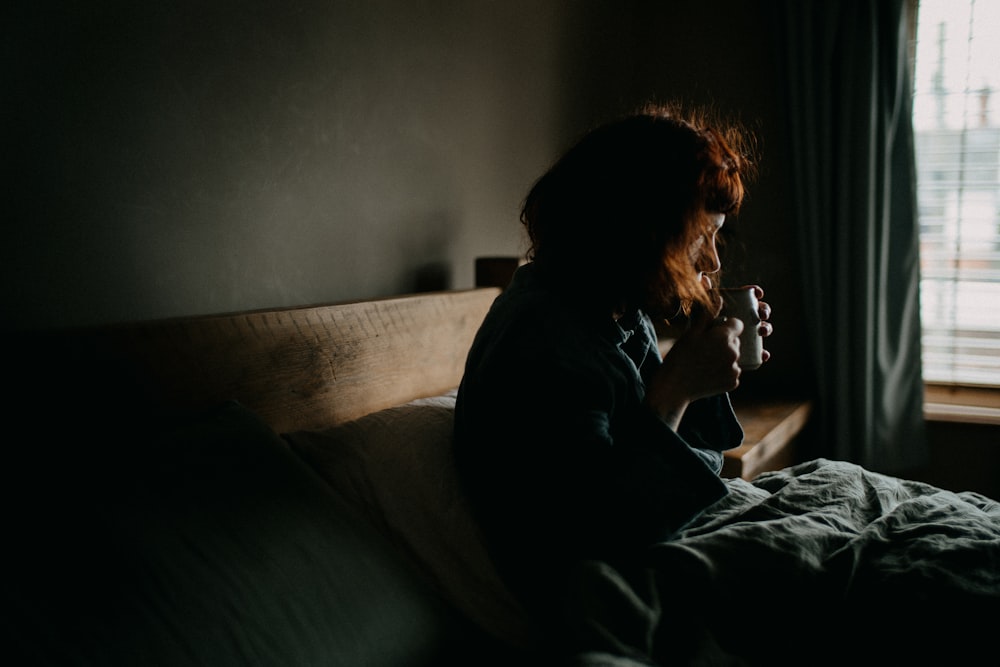 a woman sitting on top of a bed next to a window